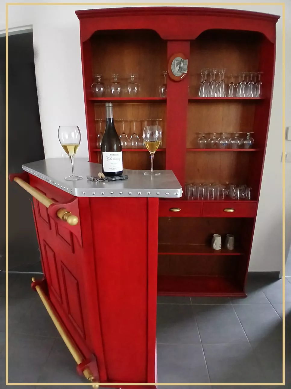 Bar et son vaisselier transformé style rétro. Faux zinc sur le plateau supérieur et faux laiton sur les barres. Rouge patiné ancien sur le reste du meuble.