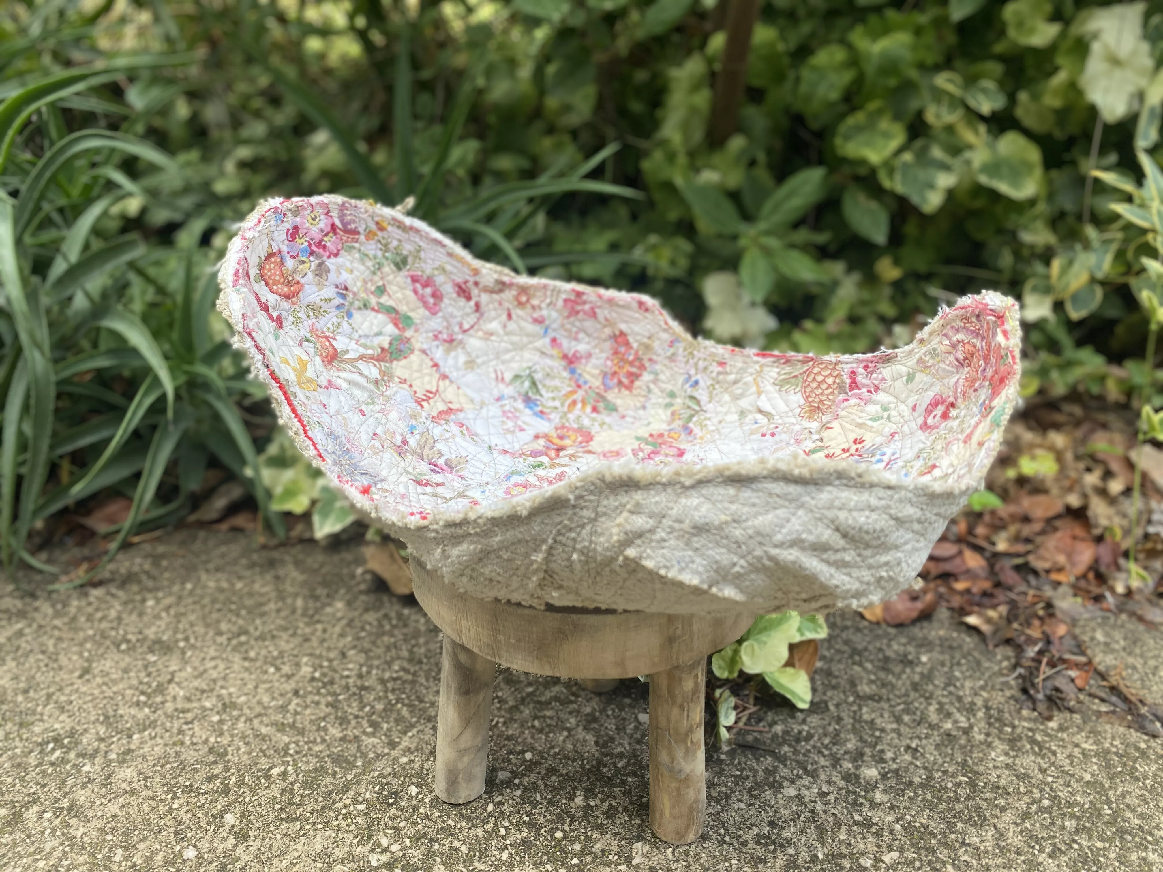 Plat en textile blanc aux fleurs roses, d'une forme rappelant la géode