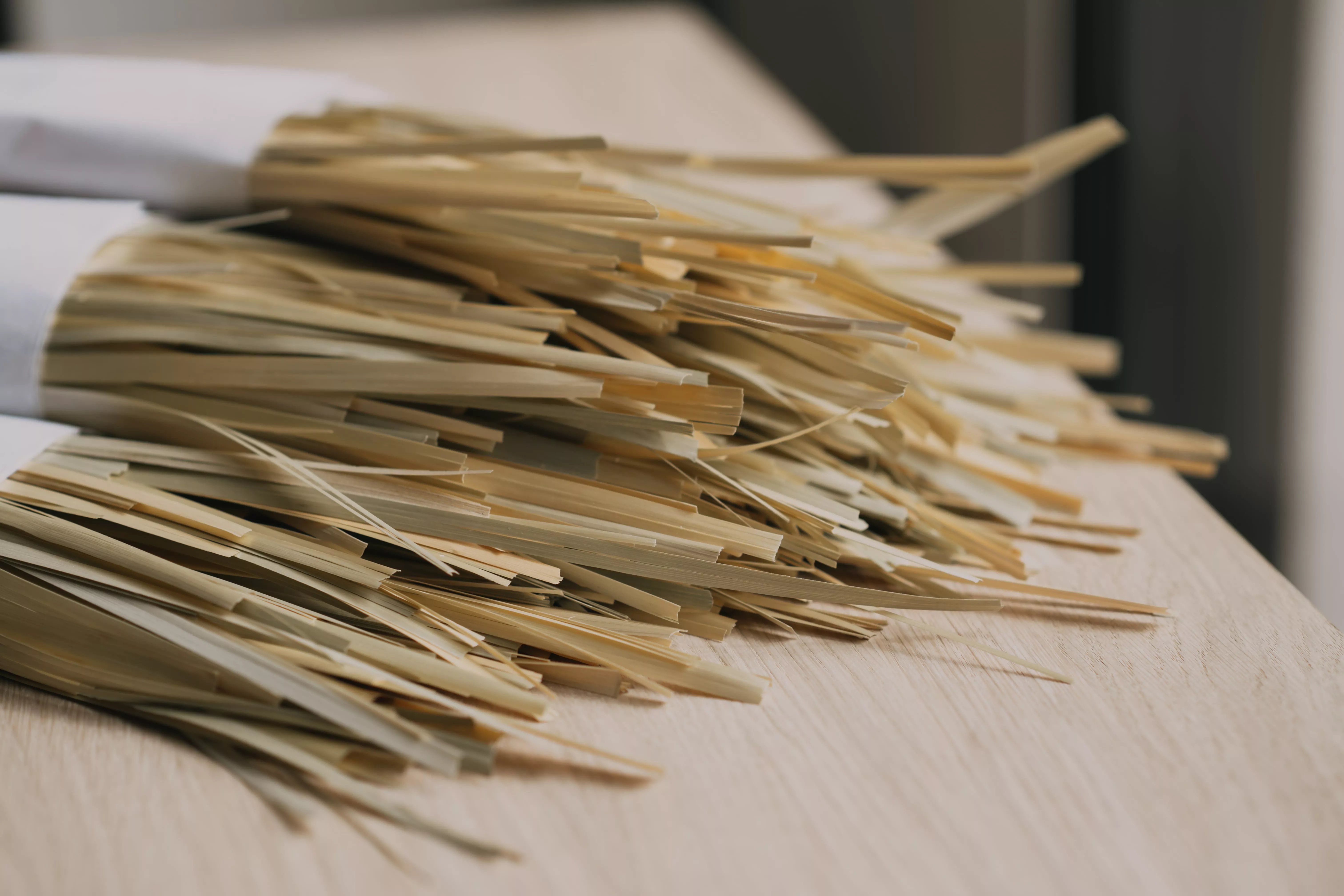 Paille de seigle aplanie en brins fins, posée sur une table en bois, prête à être utilisée en marqueterie.