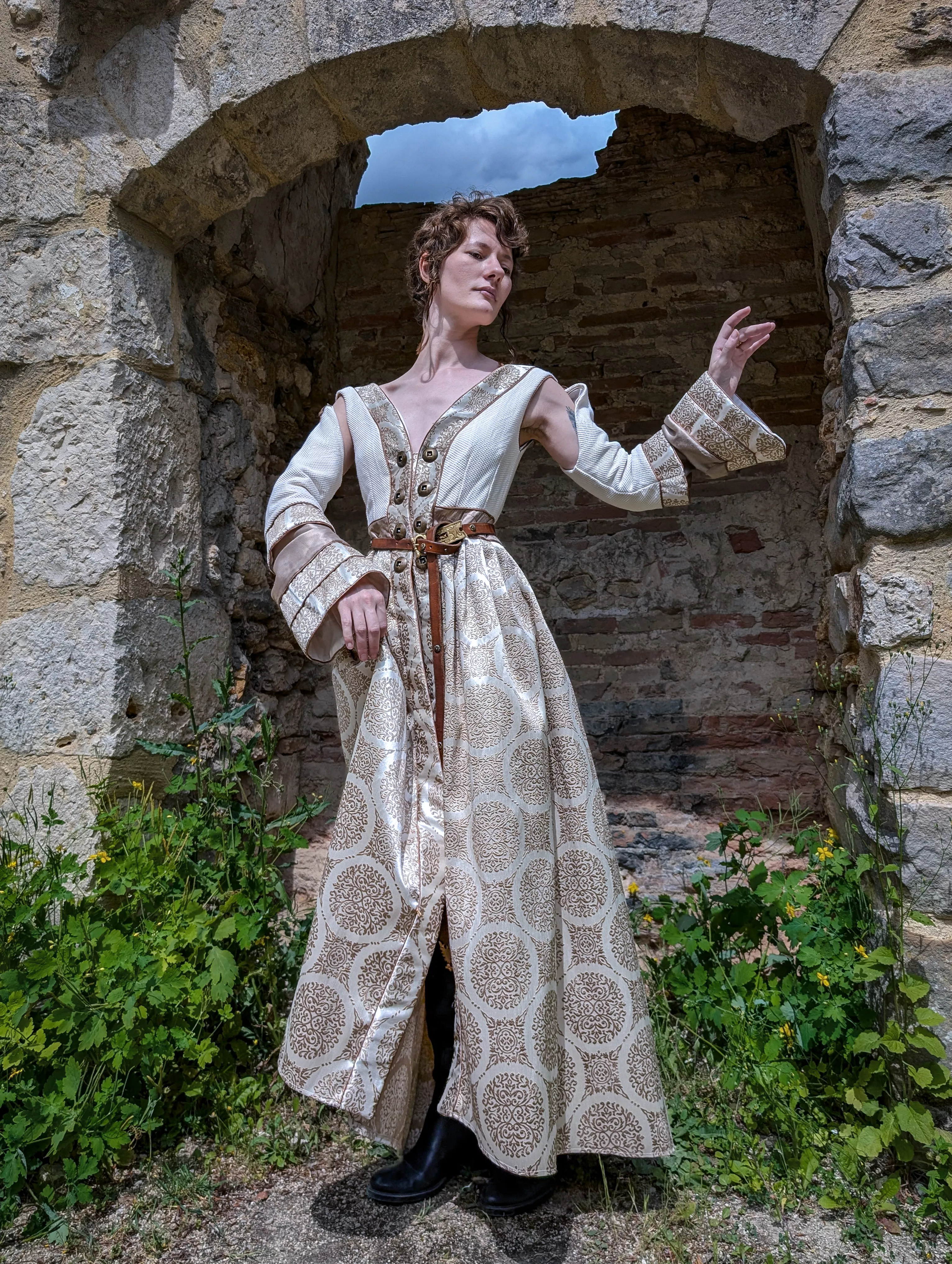 Noble femme dans sa robe brocardée dans un décors de pierre et de végétation